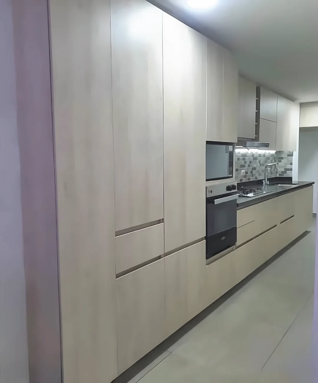 Pared de torres hasta el techo con horno y microondas empotrados y manijas en ranura